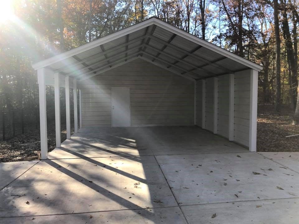 The sun is shining through the trees behind a carport.