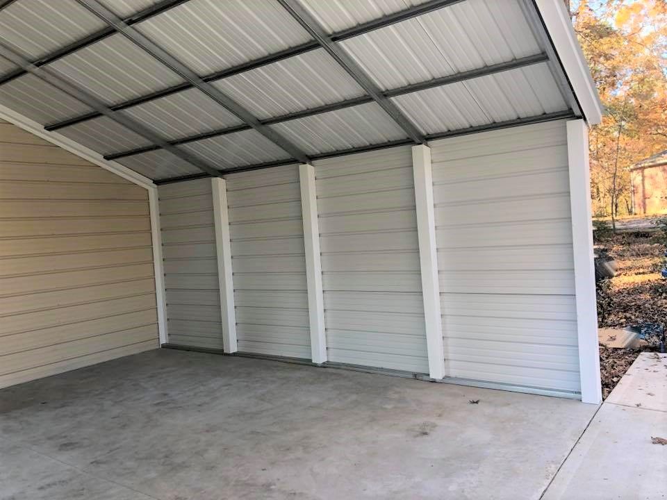 A metal garage with a roof and a concrete floor.