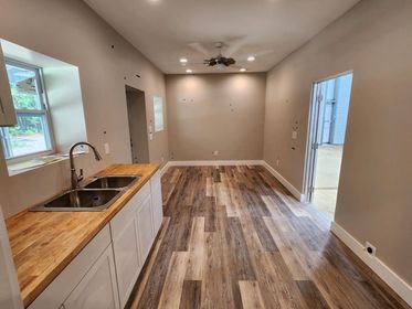 A kitchen with a sink , cabinets , and wooden floors.