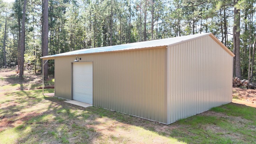 A large metal building with a white door is sitting in the middle of a grassy field.