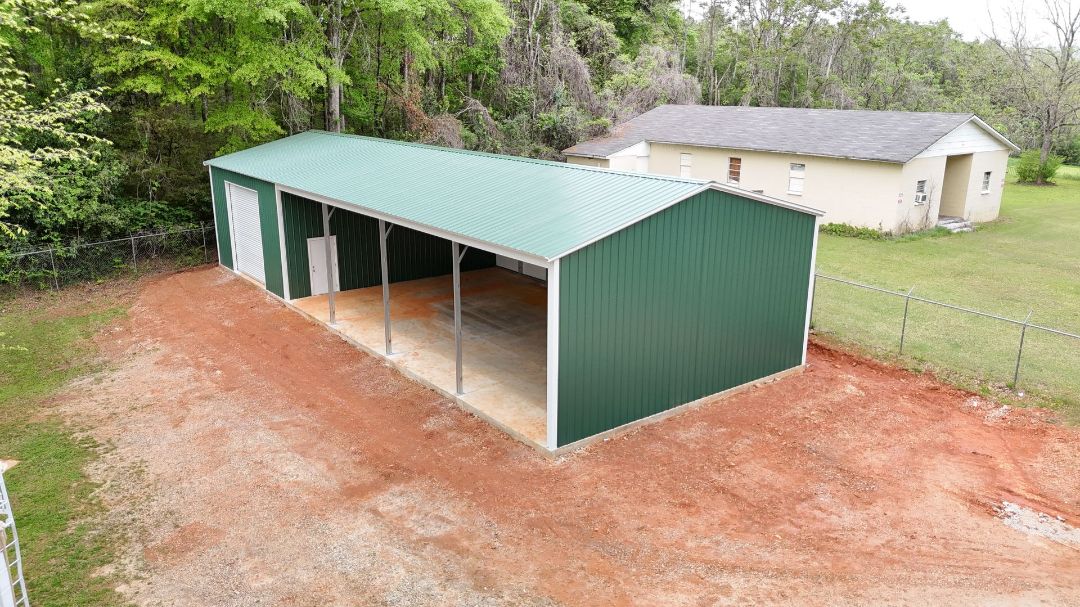 A green and white metal building with a green roof and a white garage door.