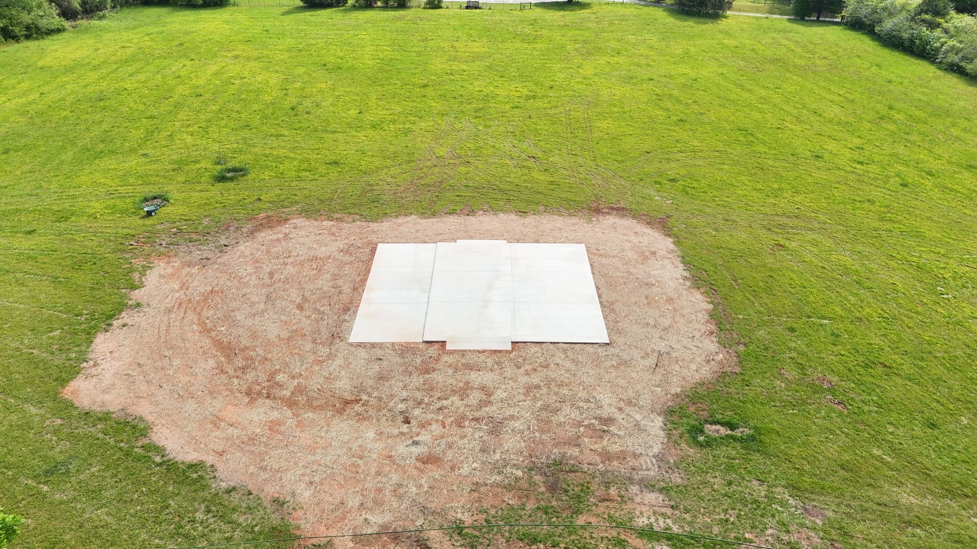 White rectangular slab set in a dirt patch surrounded by green grass, viewed from above.