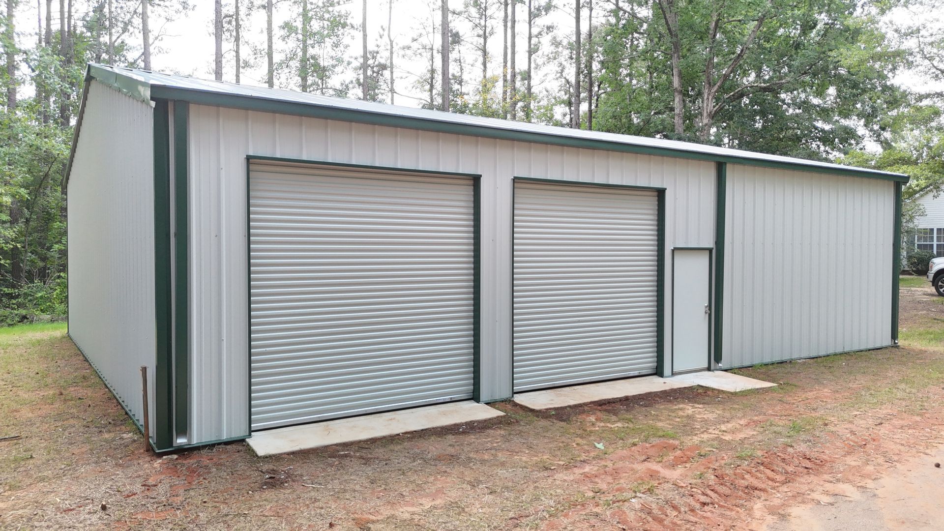 A large metal garage with two garage doors and a door.