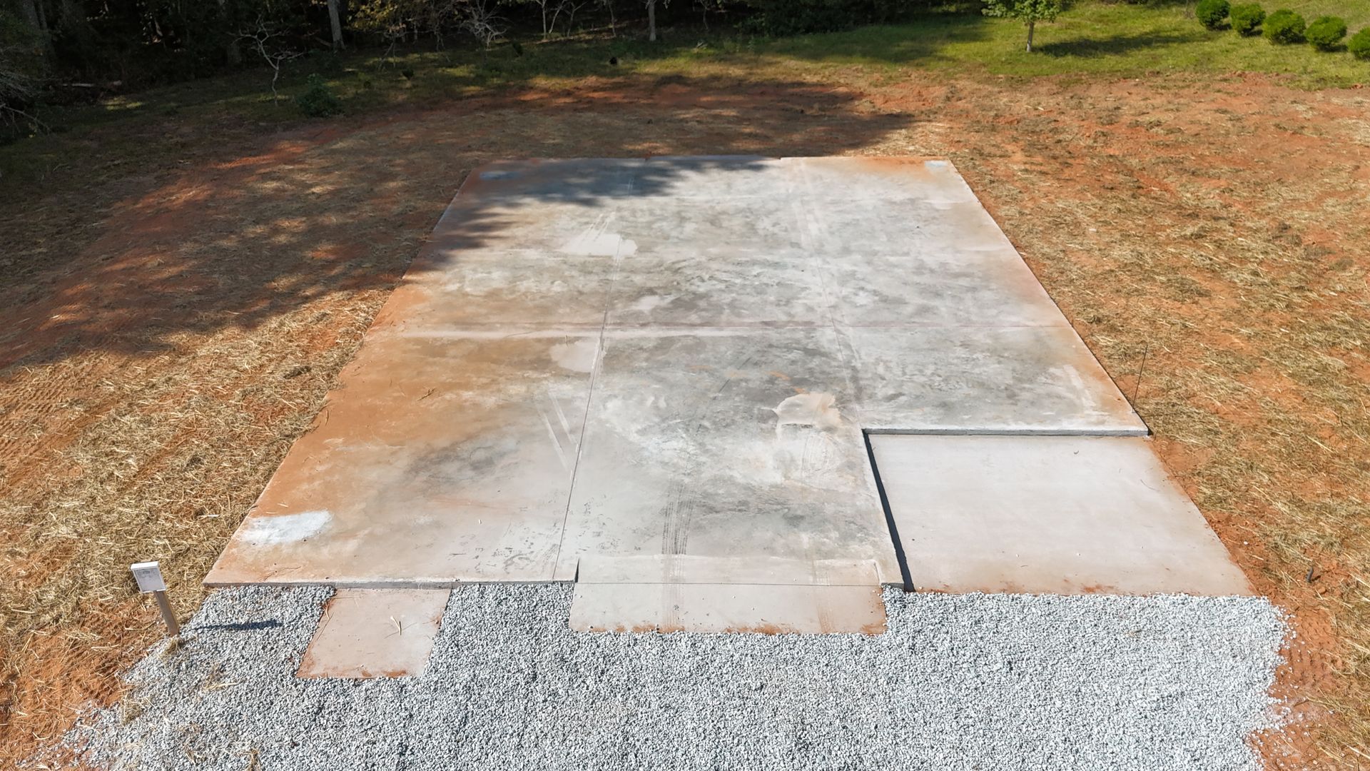Concrete walkway under construction with gravel edge in a wooded area