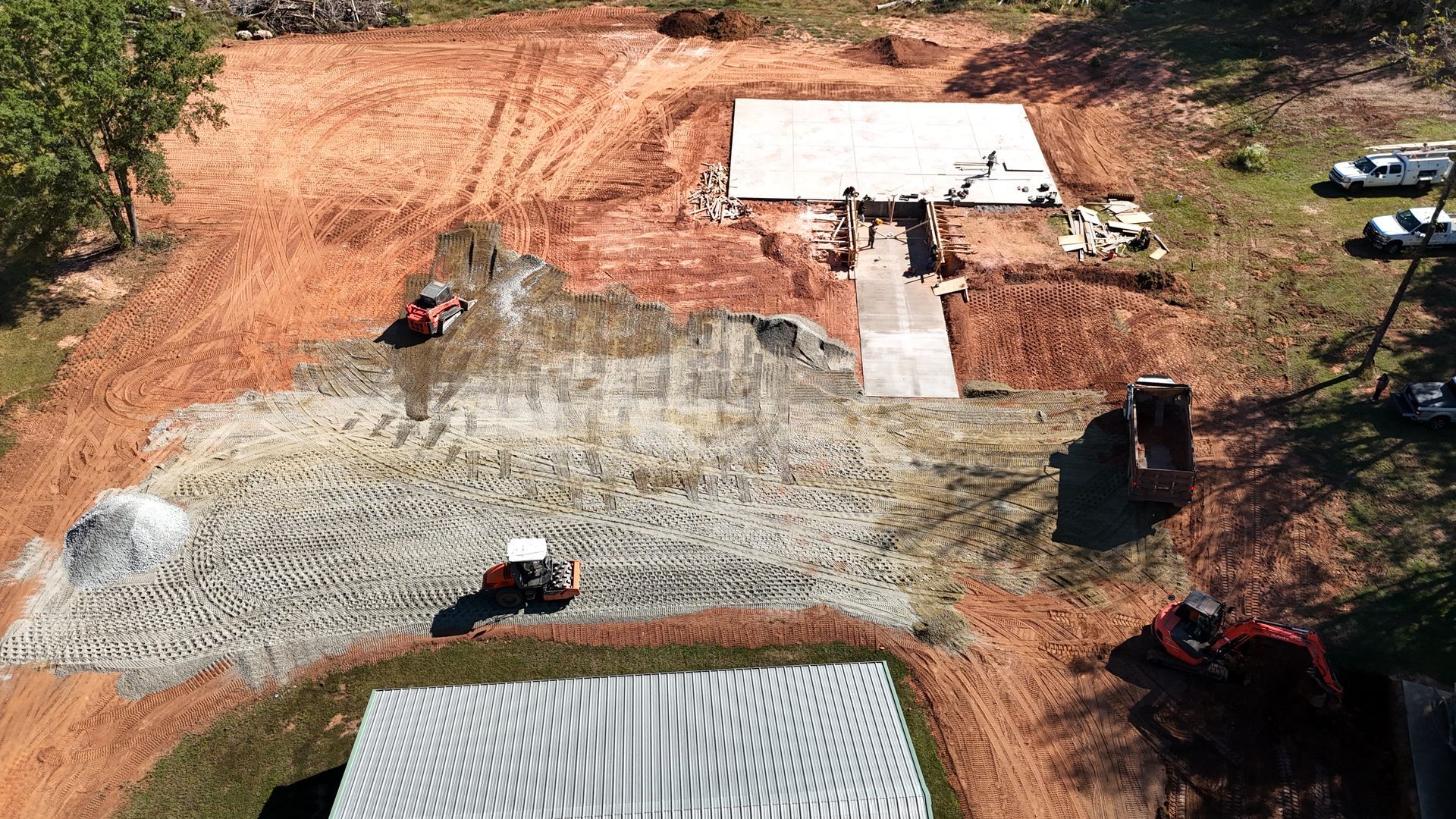 Aerial view of a construction site with grading, gravel, and heavy equipment.  A building is in the center.
