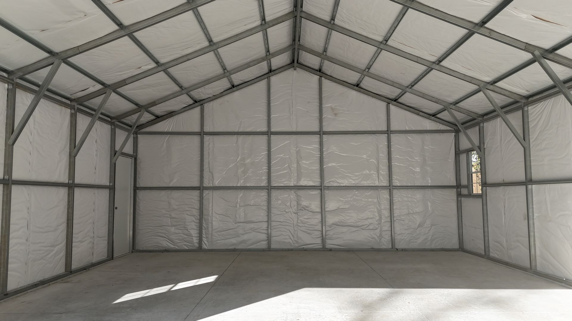 Interior view of an empty white-walled industrial building with a metal frame.