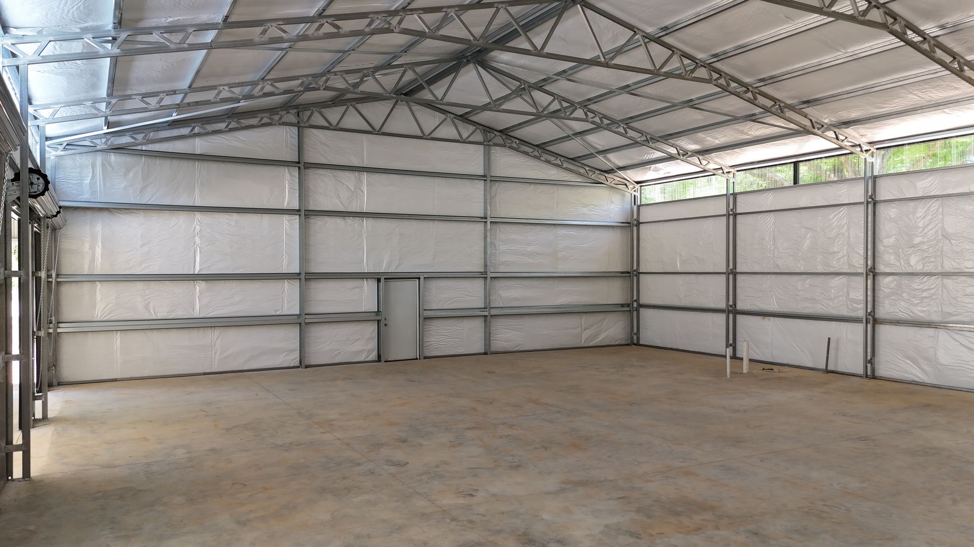 Empty metal warehouse with a concrete floor and a high truss roof