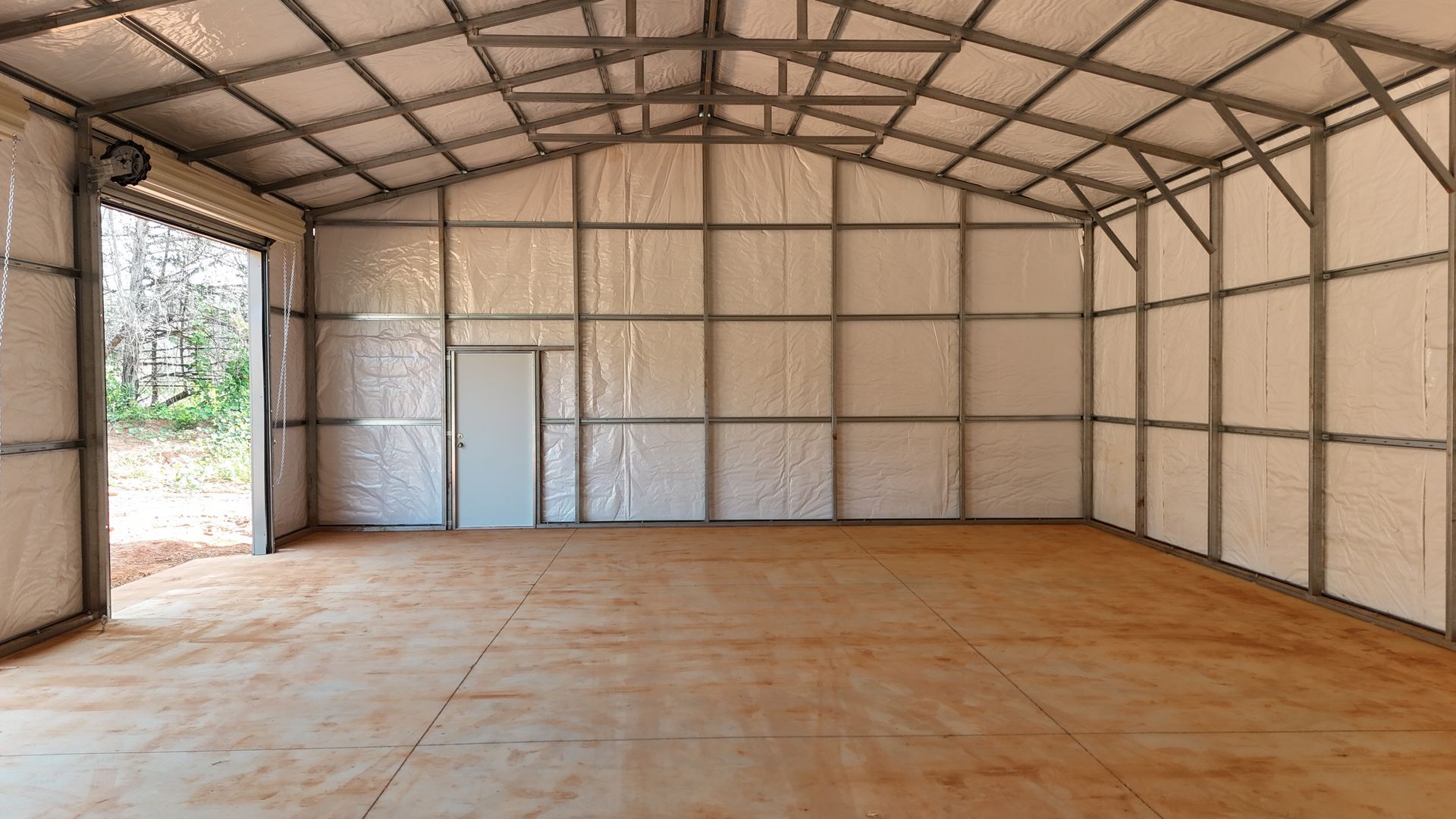 Empty metal-framed hall with beige walls, open doorway, and concrete floor.