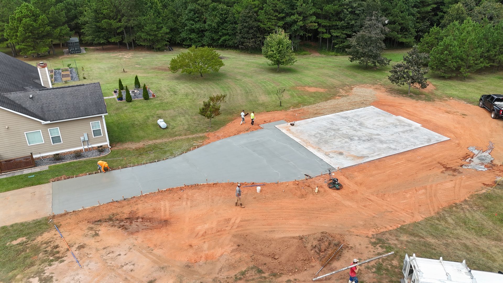 Aerial view of a house lot with a partially paved driveway and construction materials