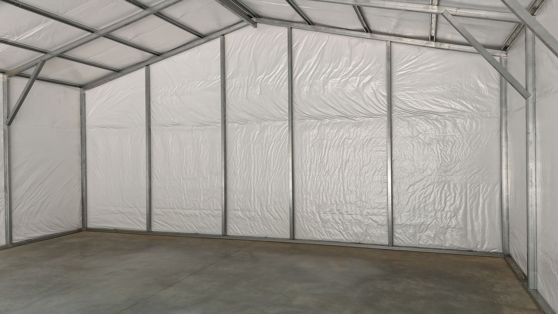 Empty metal-framed storage shed with white insulated walls and concrete floor