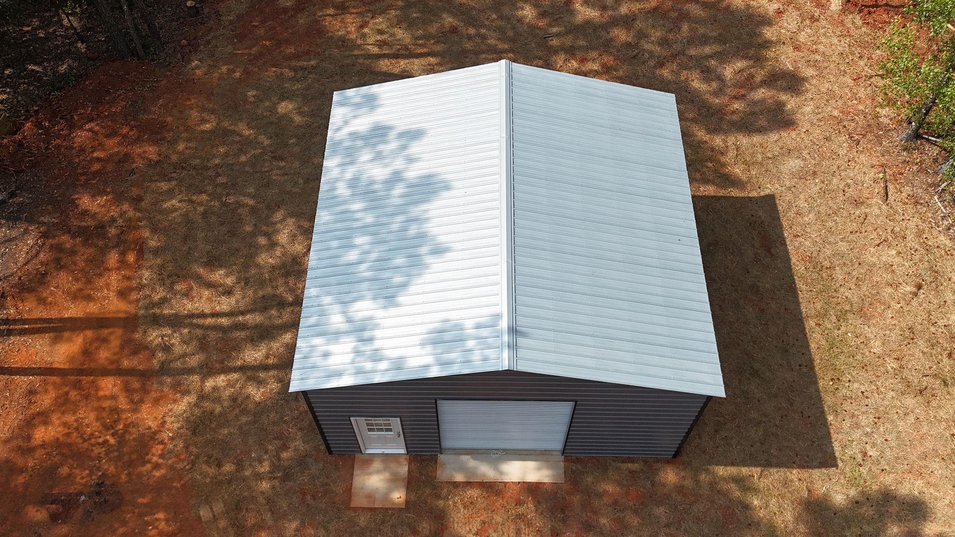 Small white-roofed house model on brown dirt, viewed from above.