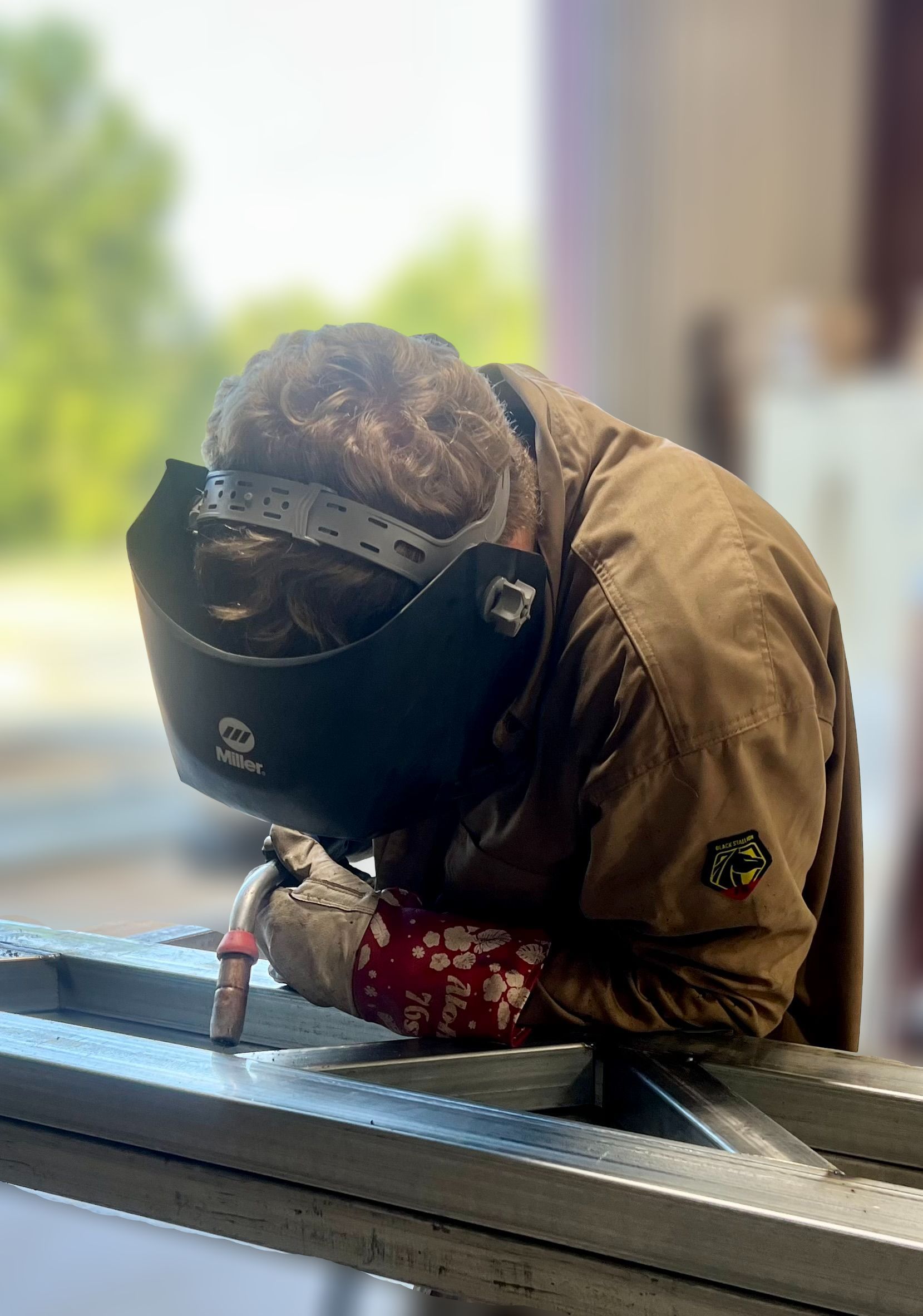 A man wearing a welding mask is welding a piece of metal.