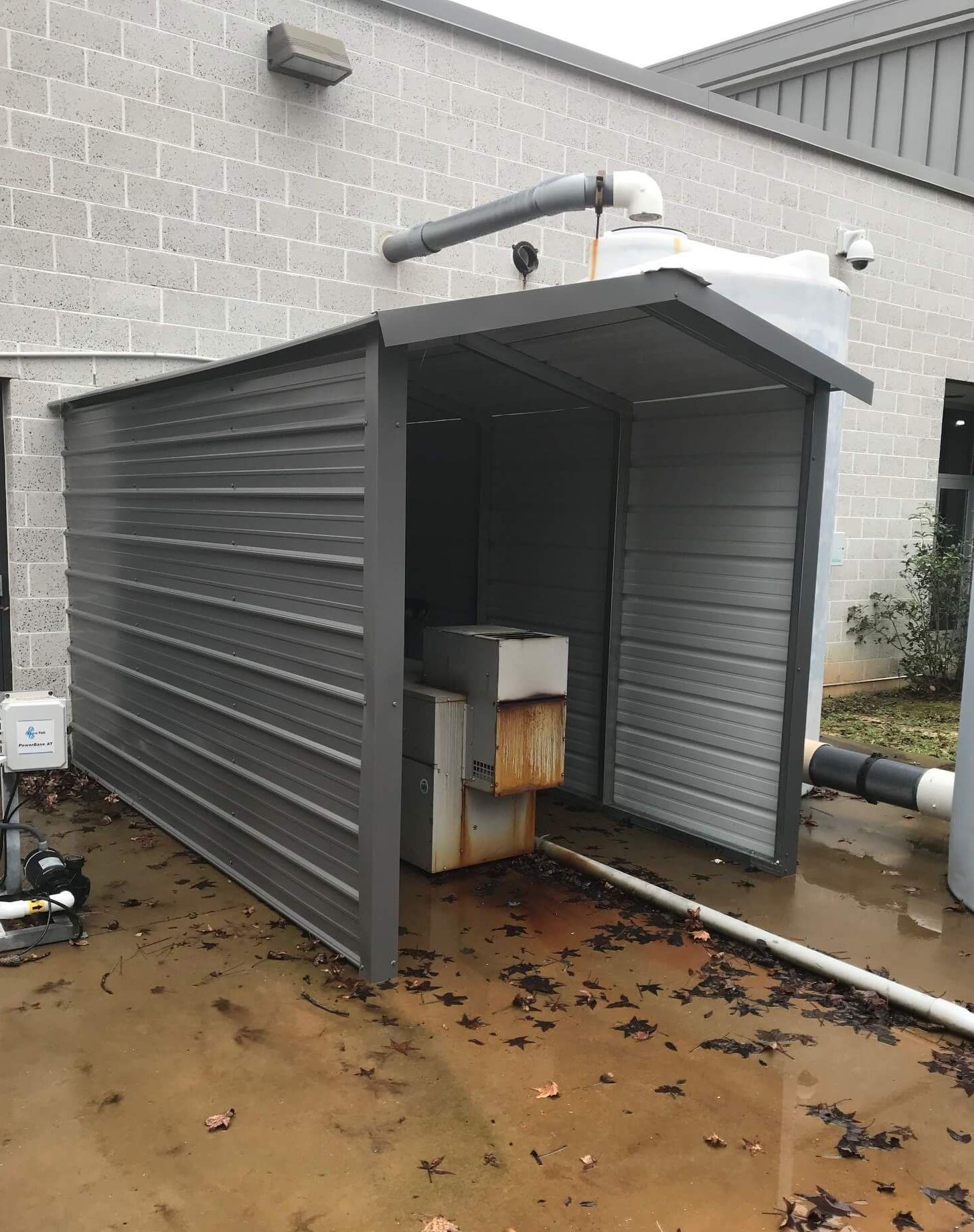 A metal shed is sitting in front of a brick building.