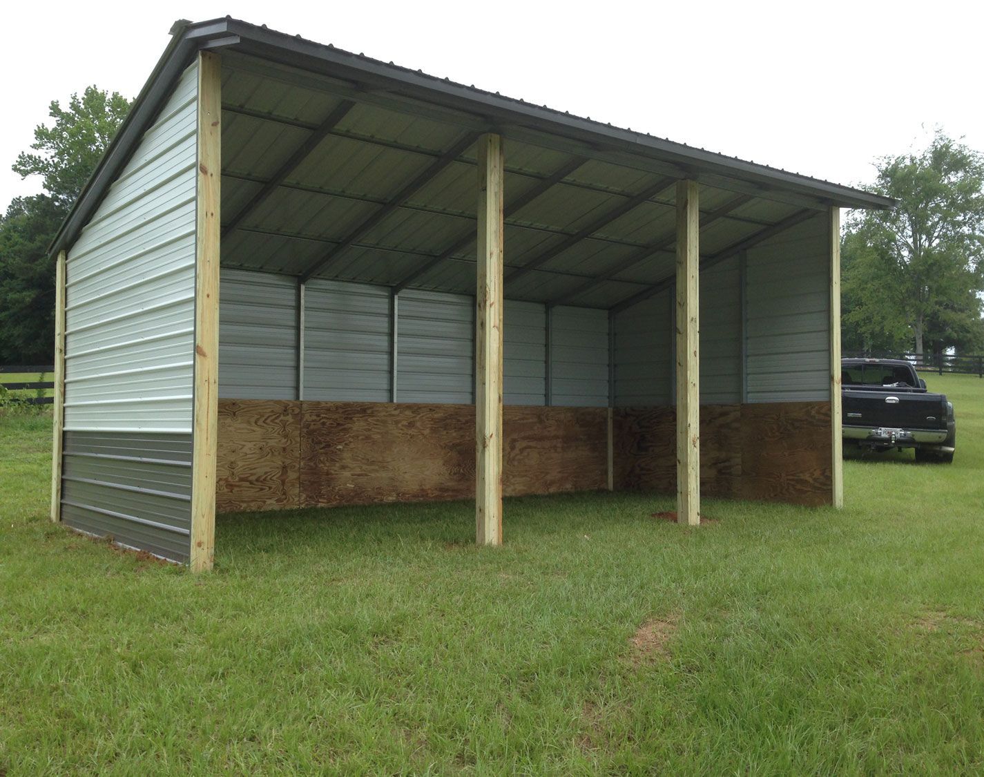 A shed is sitting in the middle of a grassy field.