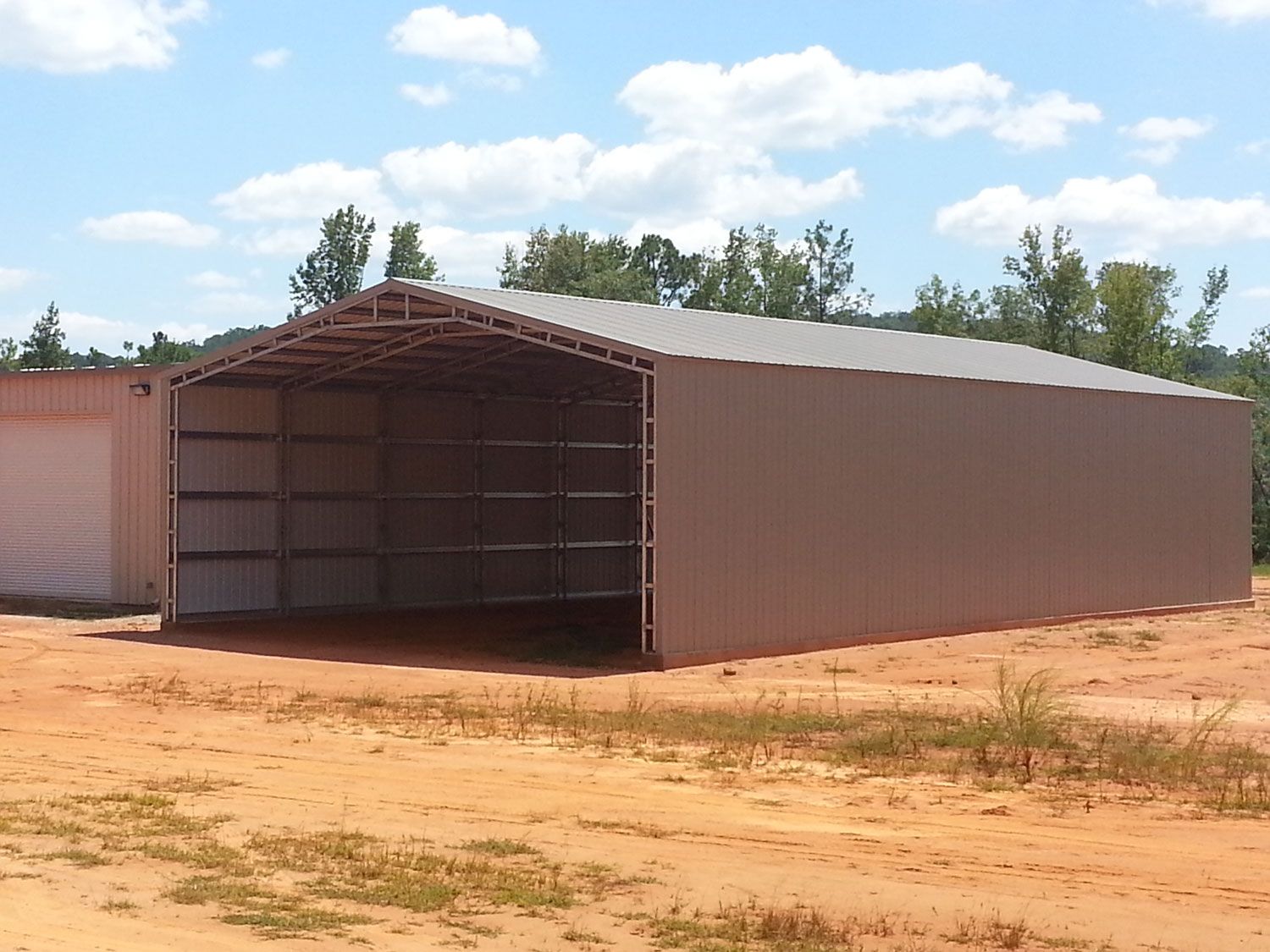 A large shed is sitting in the middle of a dirt field