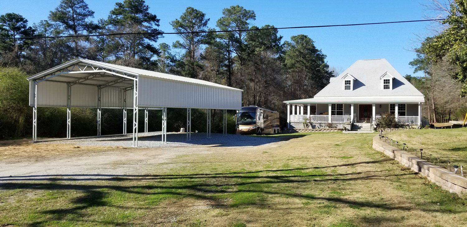 A white house with a carport in front of it.