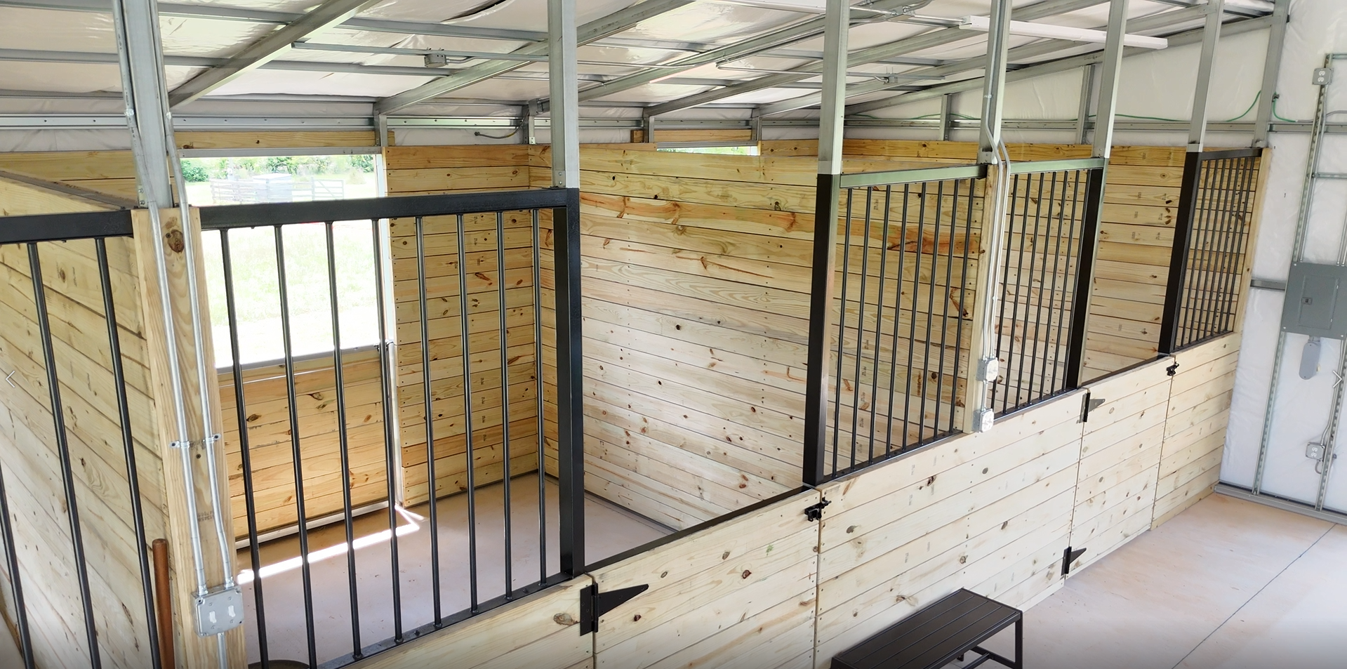 An aerial view of a horse stable with wooden walls and a metal fence.