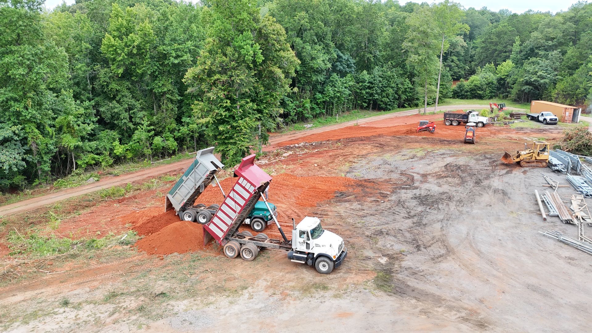 An aerial view of a dump truck dumping dirt on a construction site.