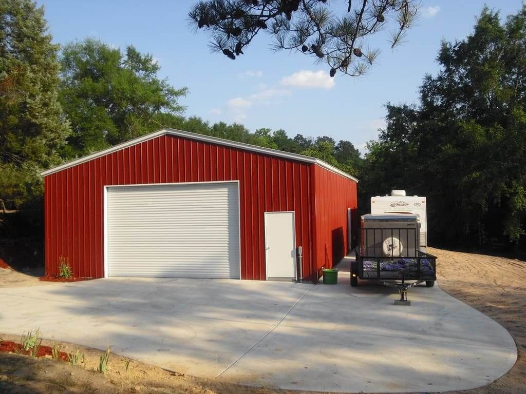 A red garage with a trailer parked in front of it