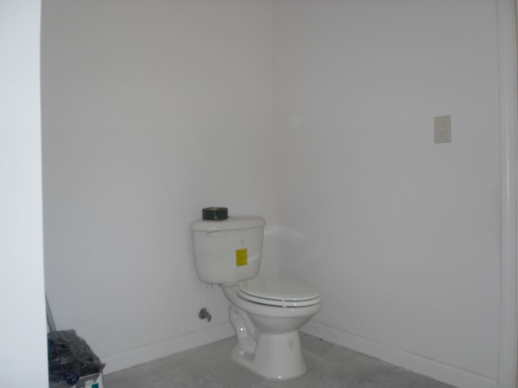 There is a toilet in the corner of a bathroom.