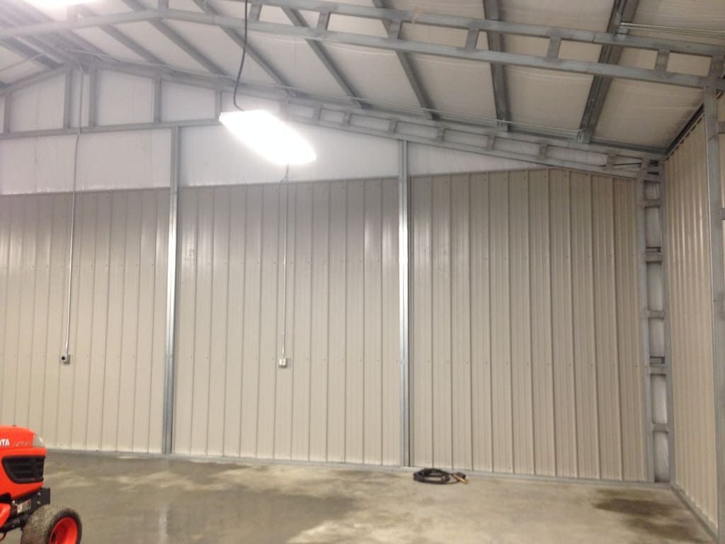 A tractor is parked inside of a metal building.