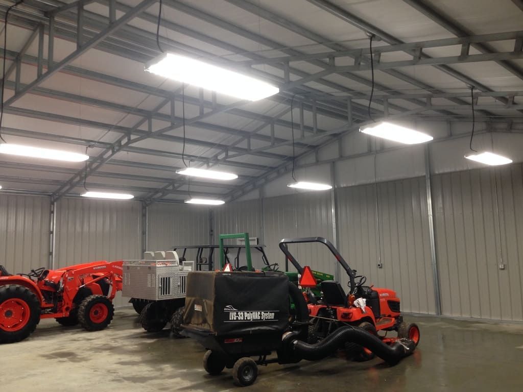 Several tractors and a vacuum cleaner are parked inside of a building