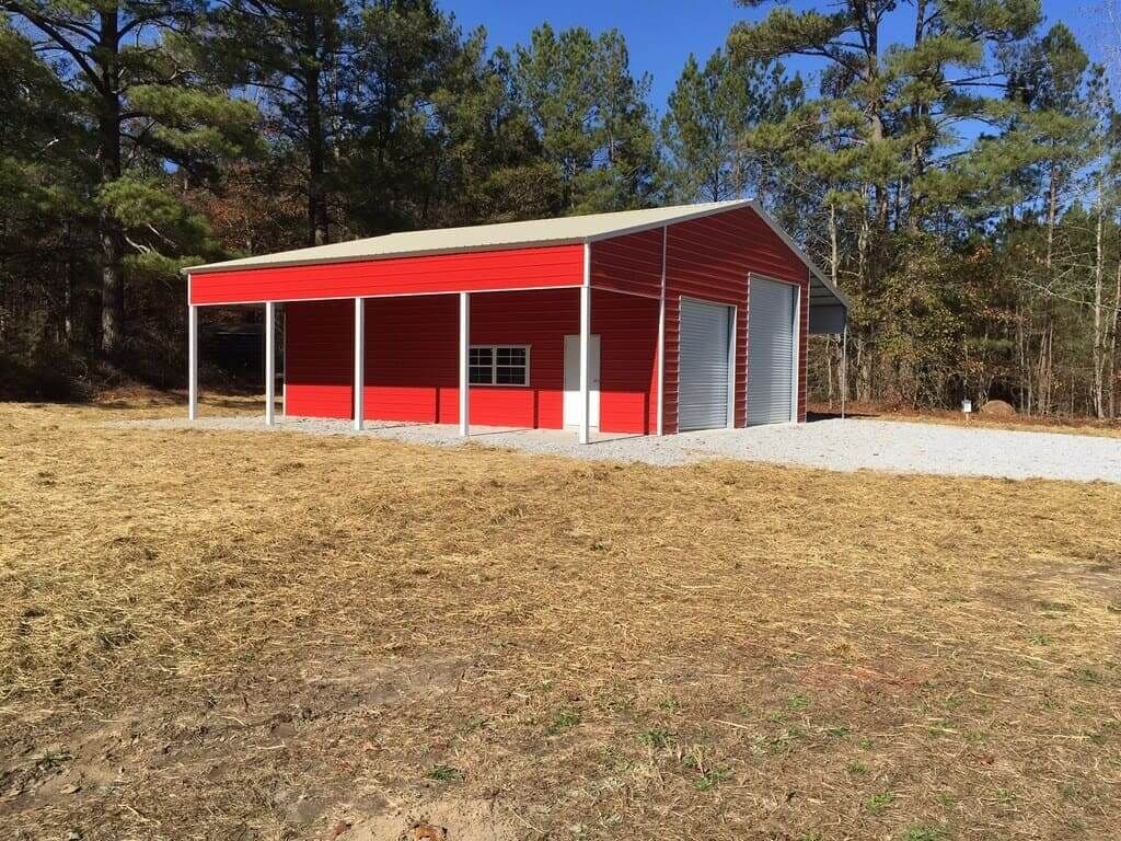 A red building with a white roof is in the middle of a field.