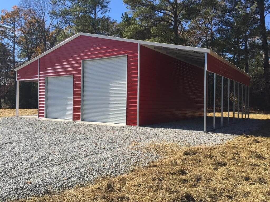 A red garage with white doors is sitting on top of a gravel road.