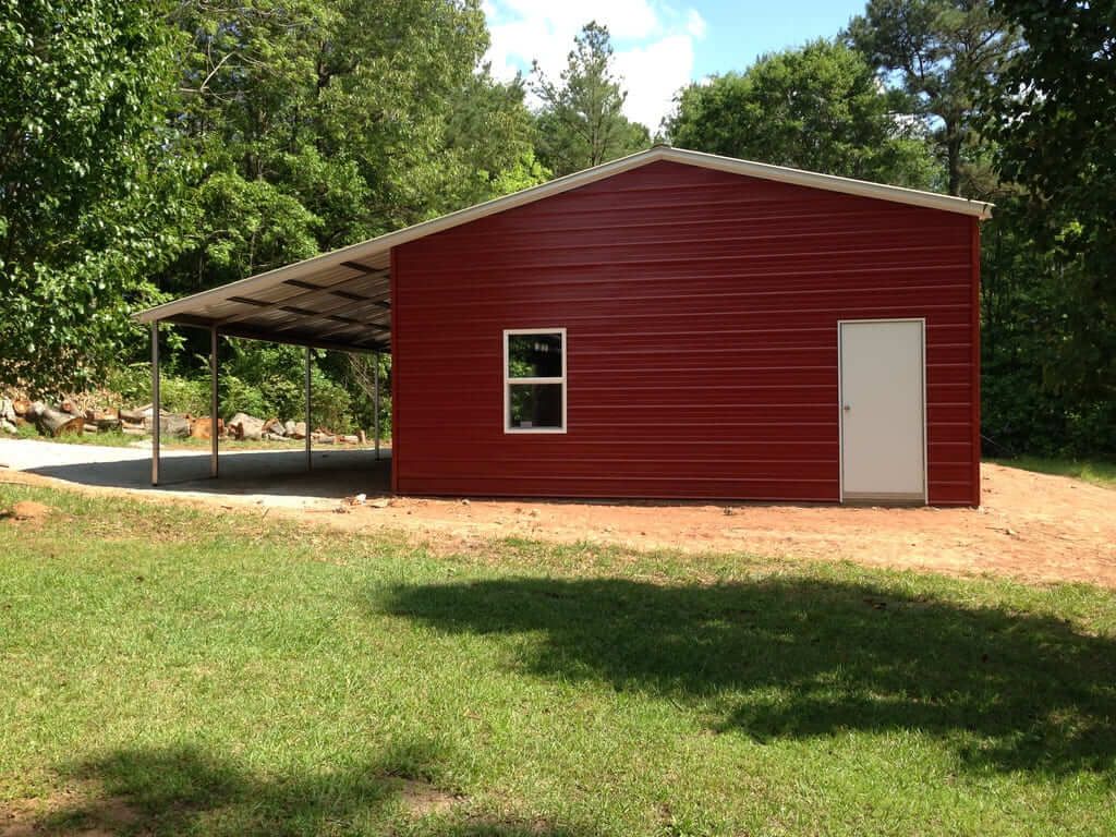 A red building with a white door and window is in the middle of a grassy field.