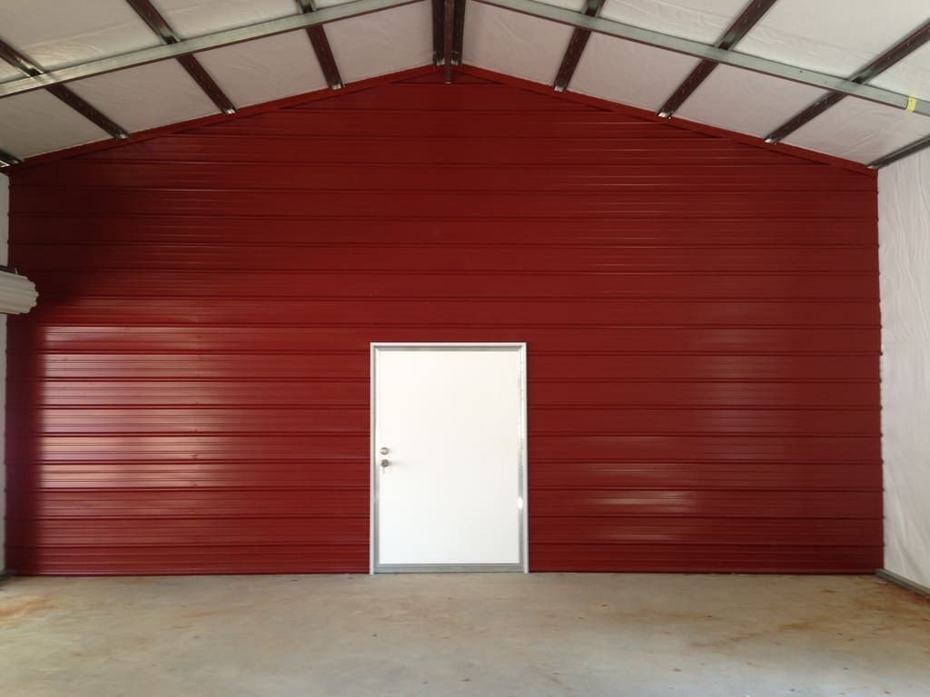 An empty garage with a red wall and a white door