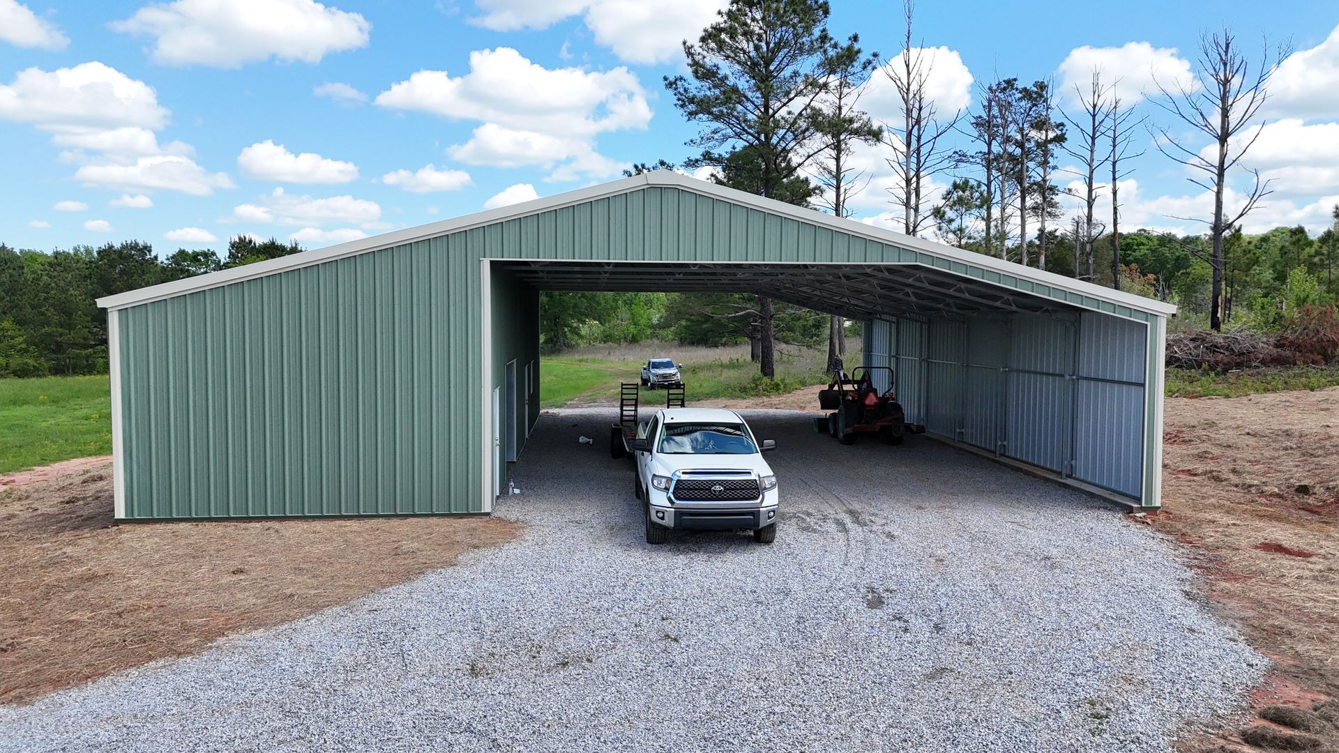 A white truck is parked in front of a metal building.
