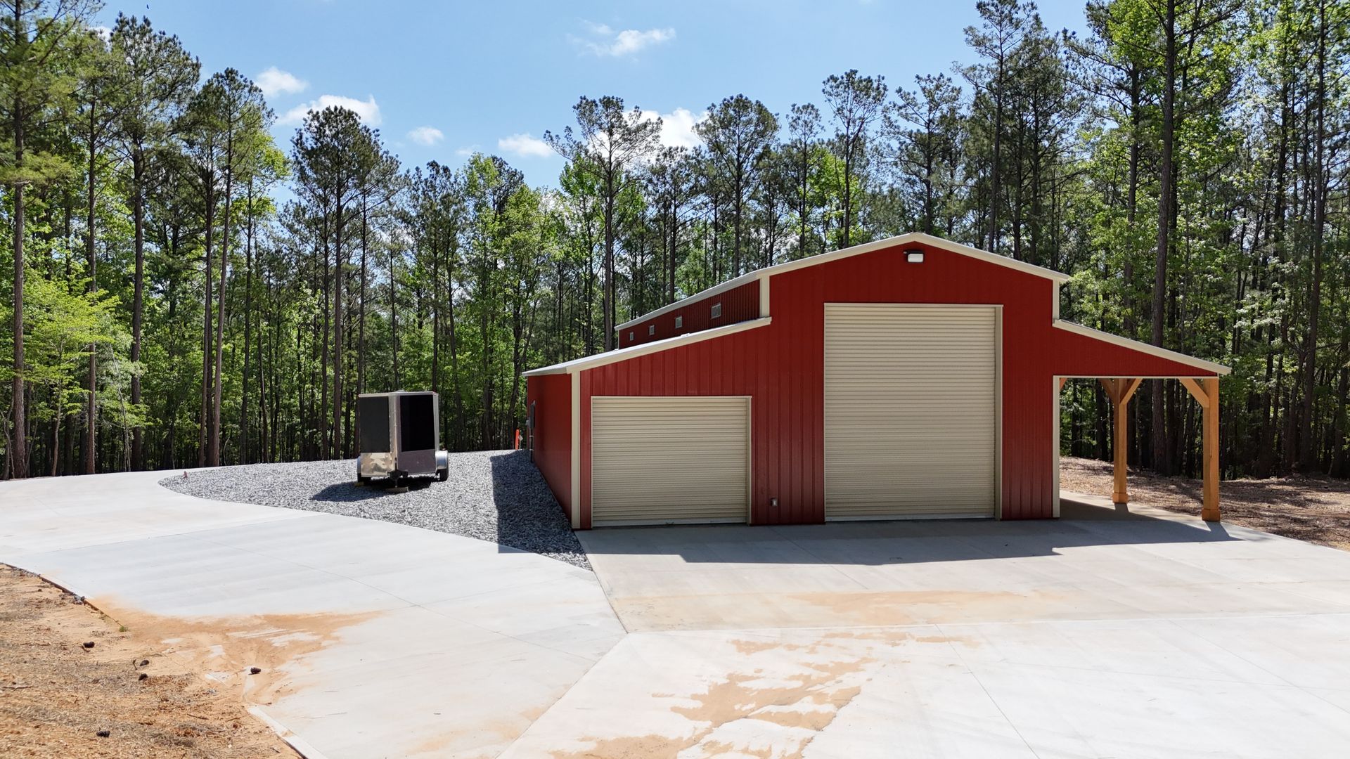 A red barn with a white door is in the middle of a forest.