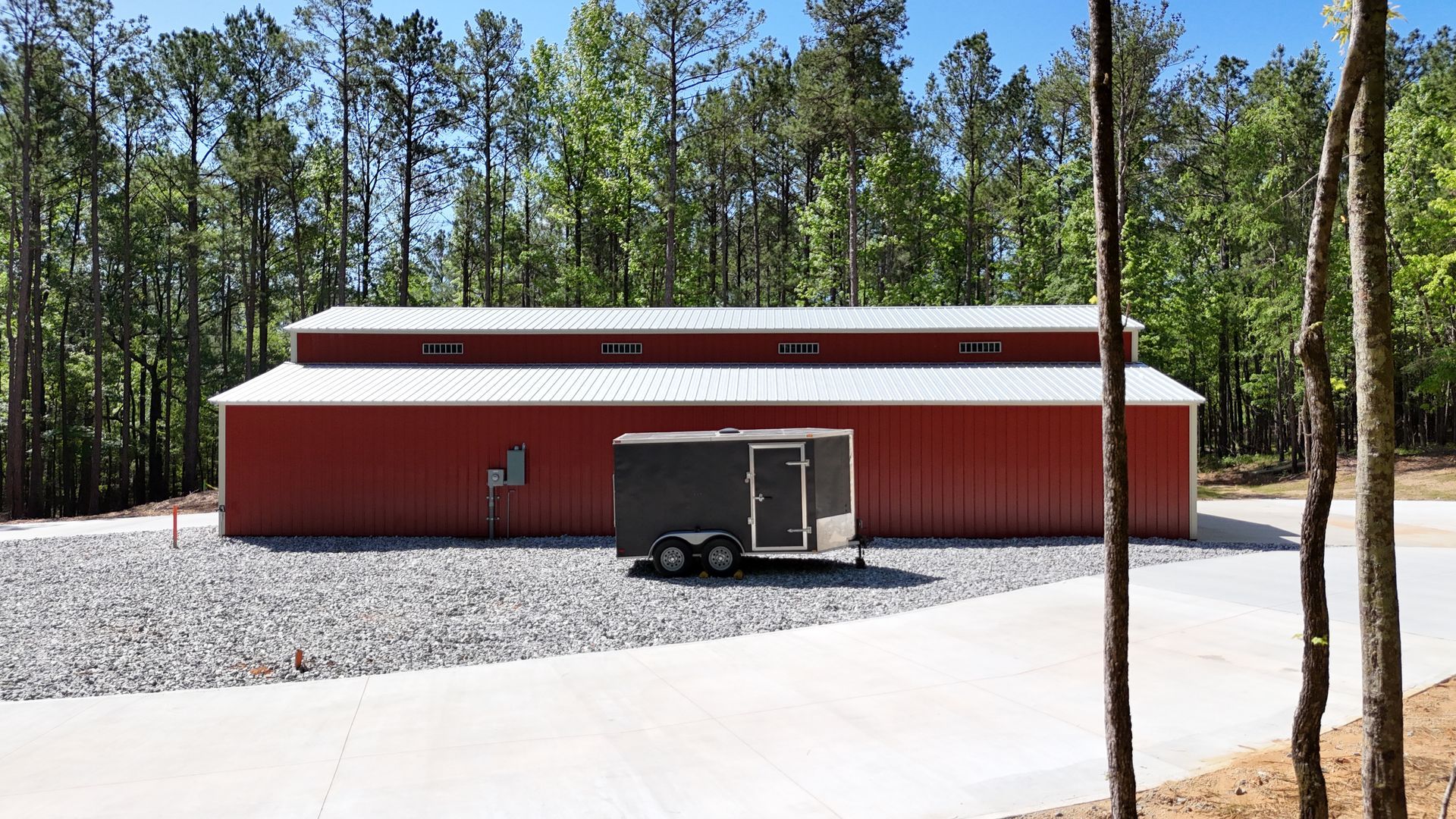 A red barn with a trailer parked in front of it.