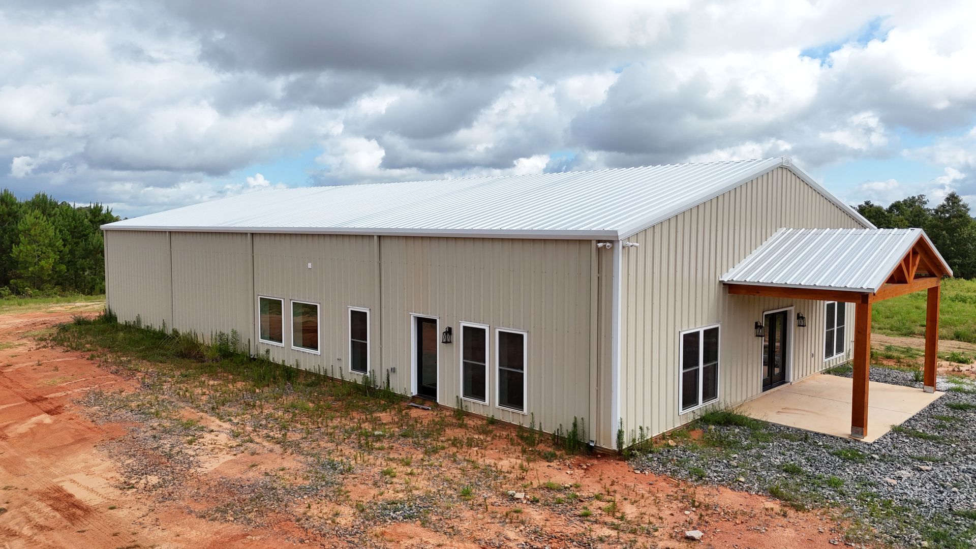 A large building with a white roof is sitting in the middle of a dirt field.