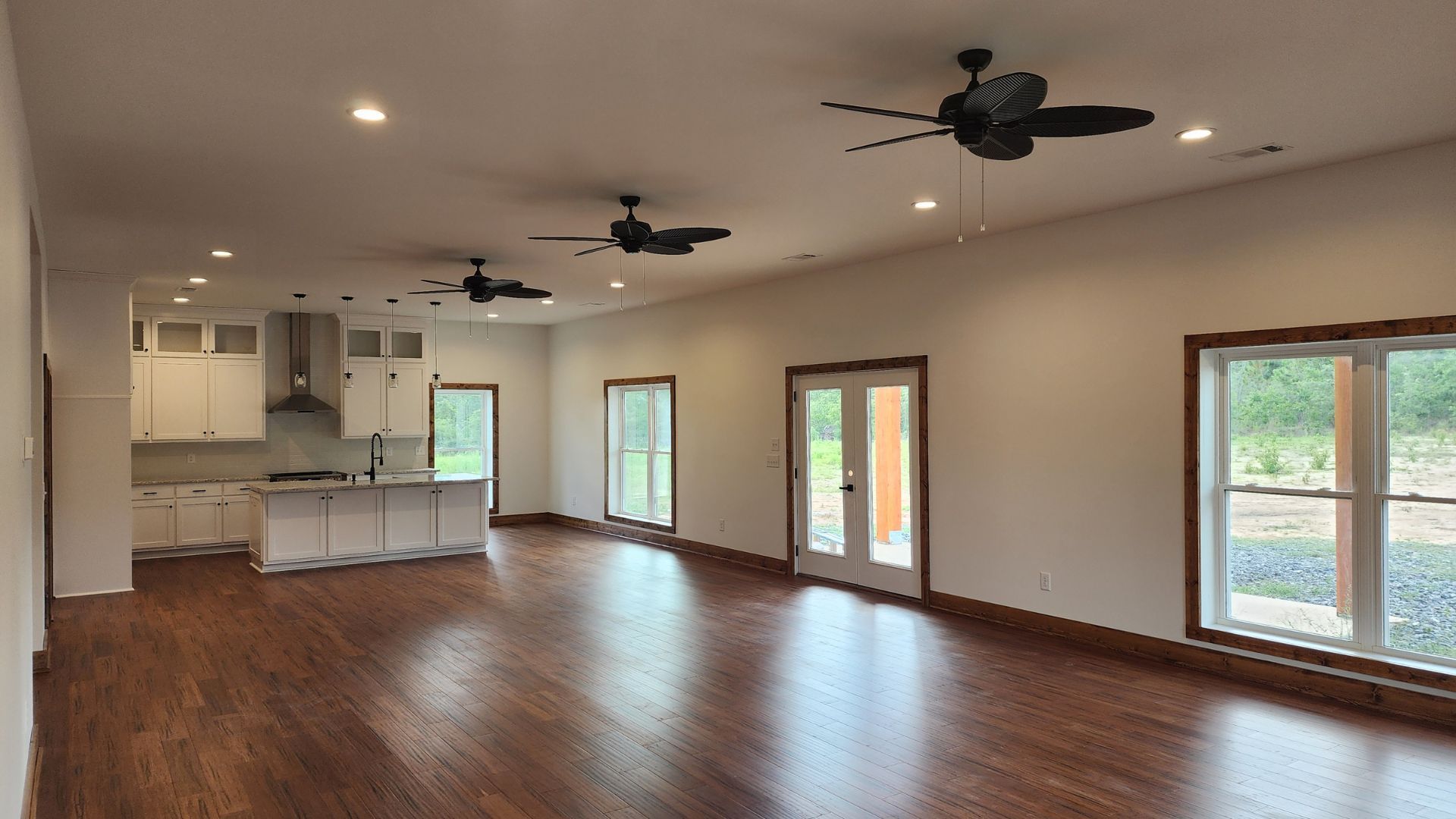 A large empty room with hardwood floors and ceiling fans.