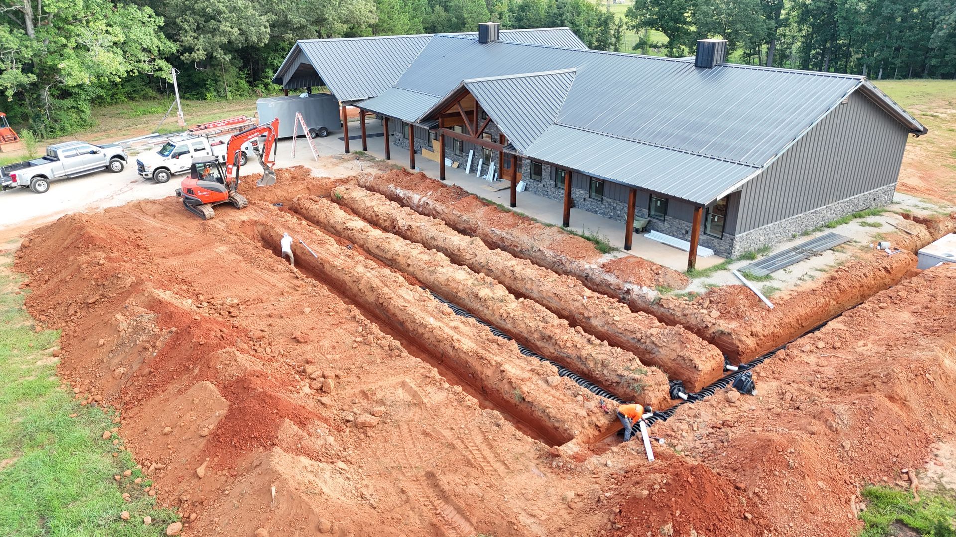 Excavation and trenching around a gray-roofed house at a construction site