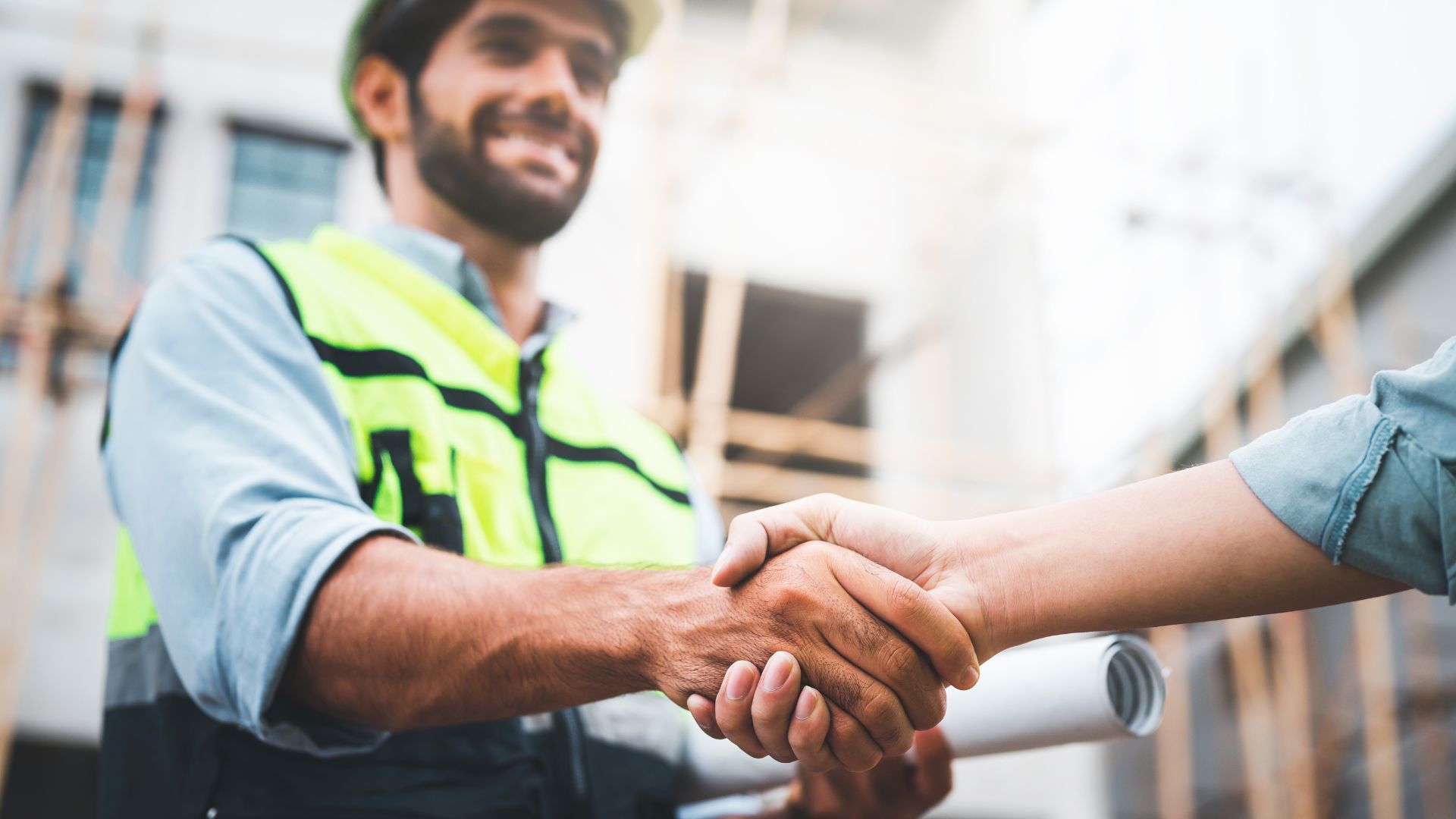 A construction worker is shaking hands with a woman at a construction site.