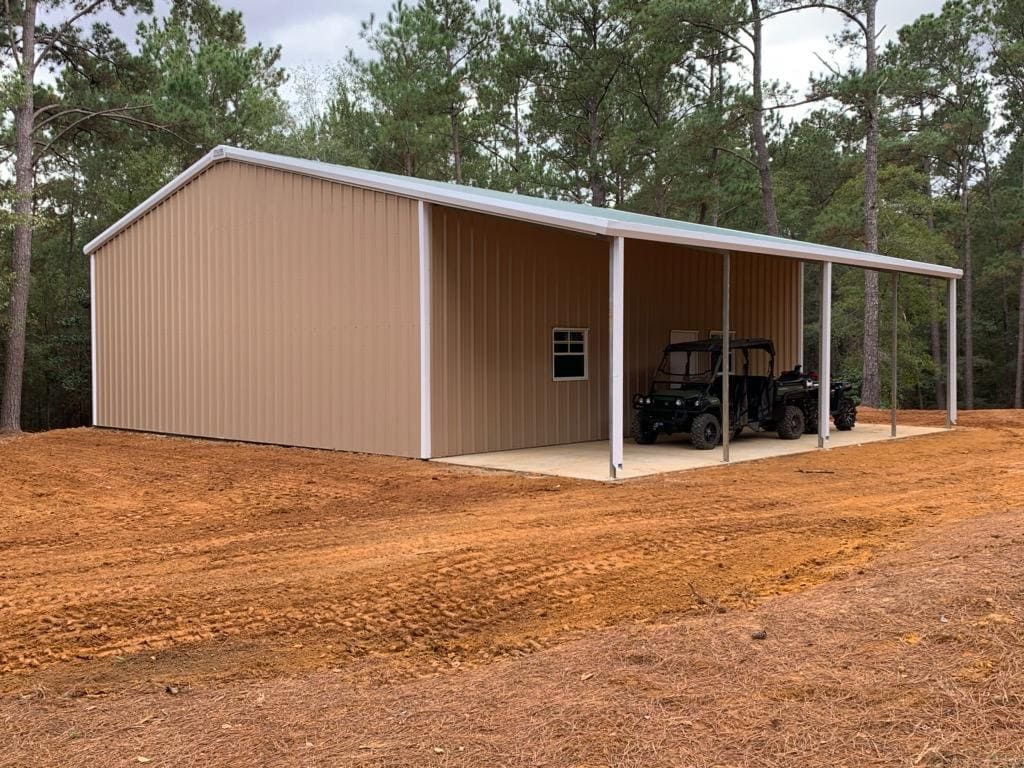 A metal building with two atvs parked inside of it.