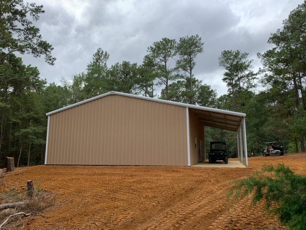 A car is parked under a shed in a dirt field.