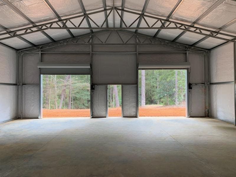 A large empty building with two garage doors open.