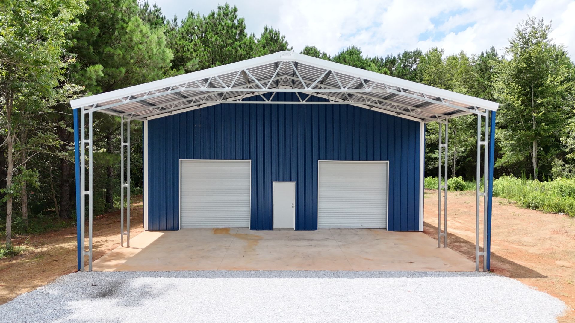 A blue metal building with two garage doors and a canopy.