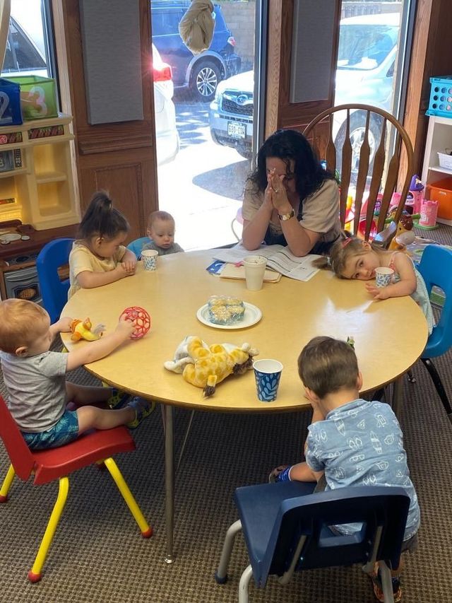 A group of children are sitting around a table in a room.