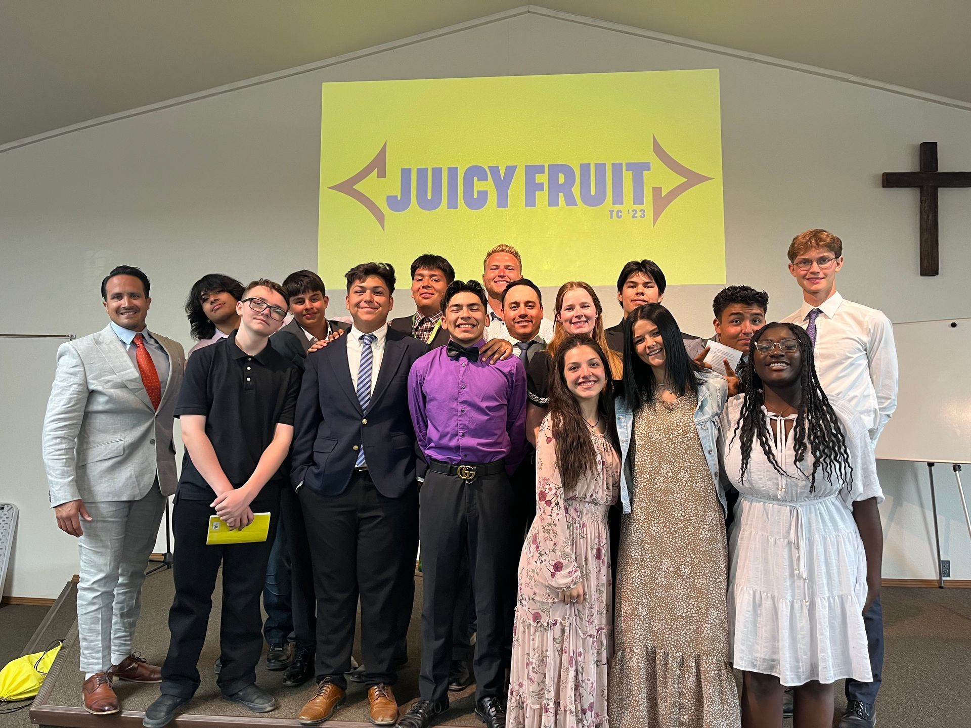 A group of people are posing for a picture in front of a juicy fruit sign.