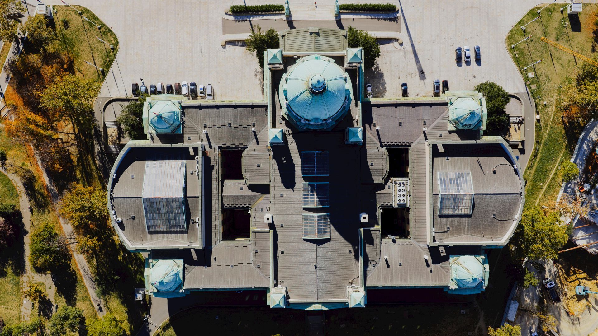 Aerial view of a castle-like building with blue domes and symmetrical wings surrounded by trees.