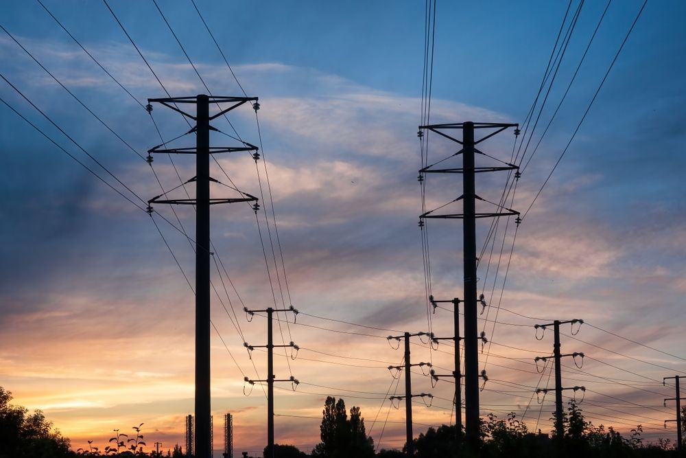 Utility poles and power lines silhouetted against a colorful sunset sky