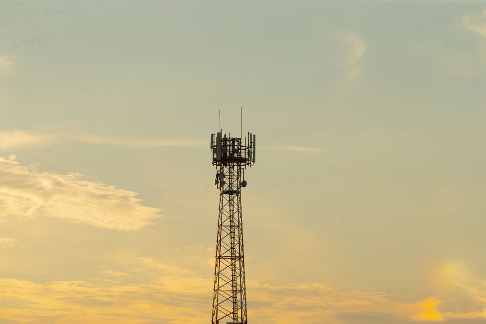 Cell tower silhouetted against a golden sunset sky