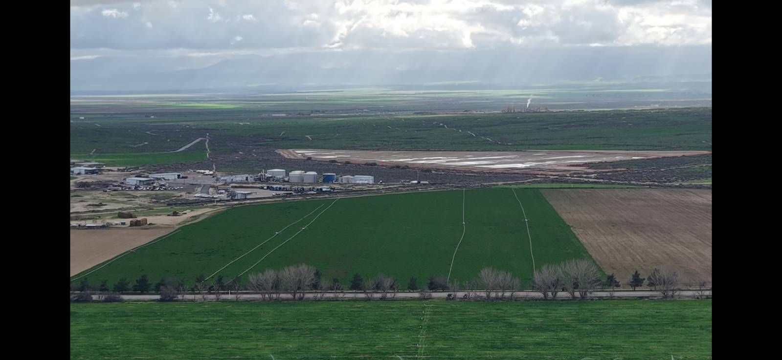 Aerial view of green farmland with a stormy cloudy sky and distant horizon