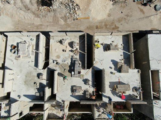 Aerial view of a building roof with solar panels, HVAC units, and one person in a red shirt.