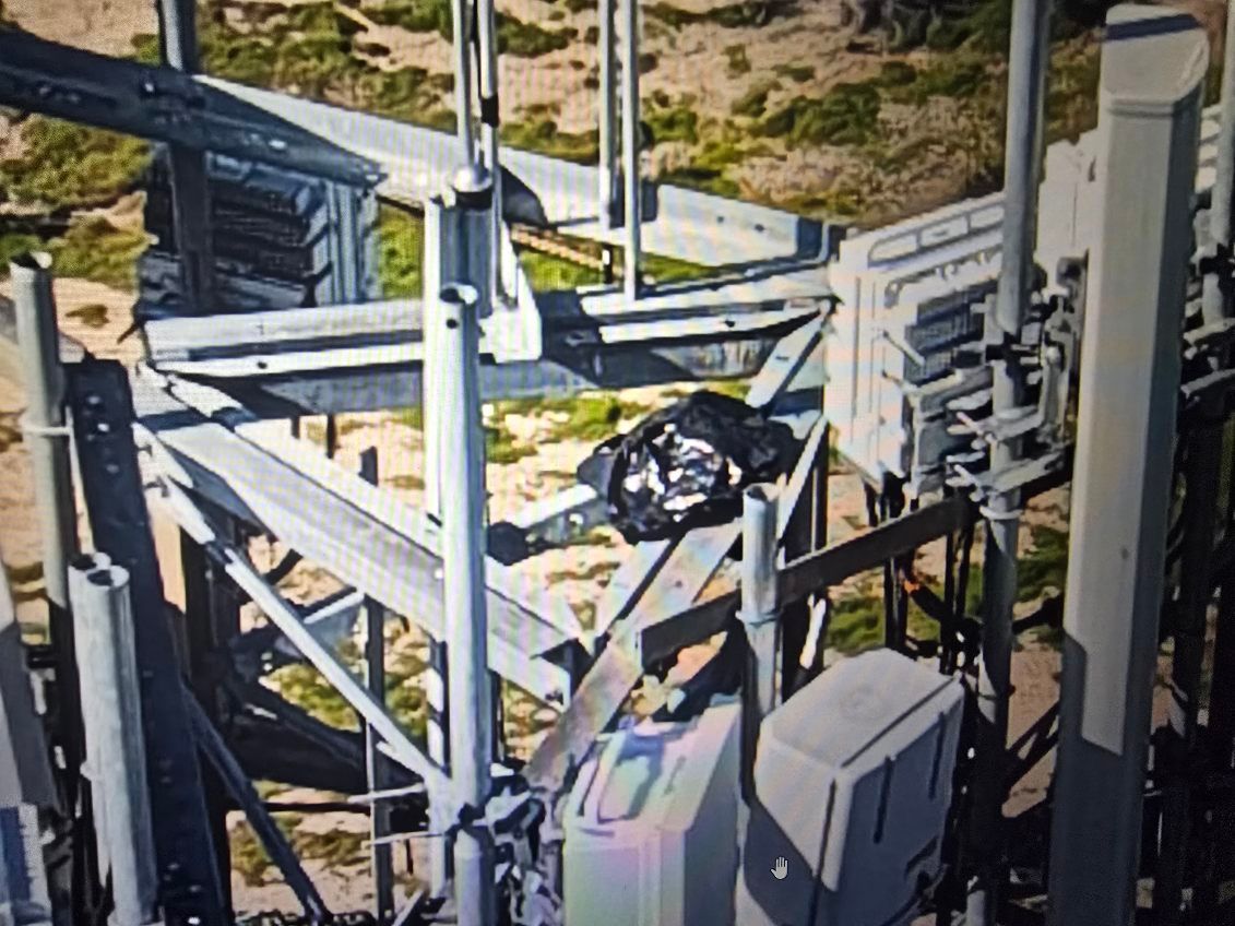 Industrial tower structure with cables and equipment against a rocky landscape