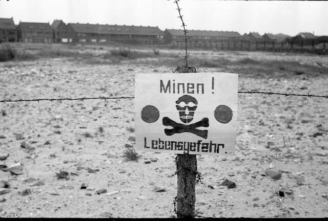 Waarschuwingsbord voor mijnen met doodskop en gekruiste botten; daaronder staat 